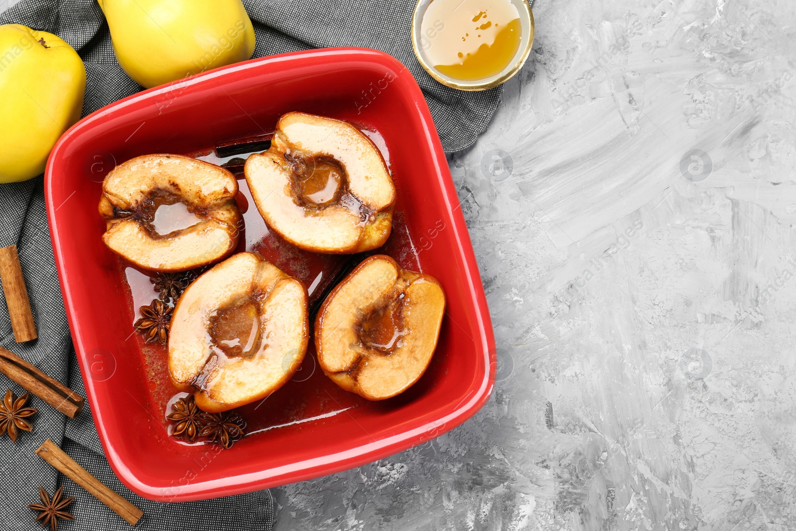 Photo of Tasty baked quinces with honey in dish on grey textured table, flat lay. Space for text