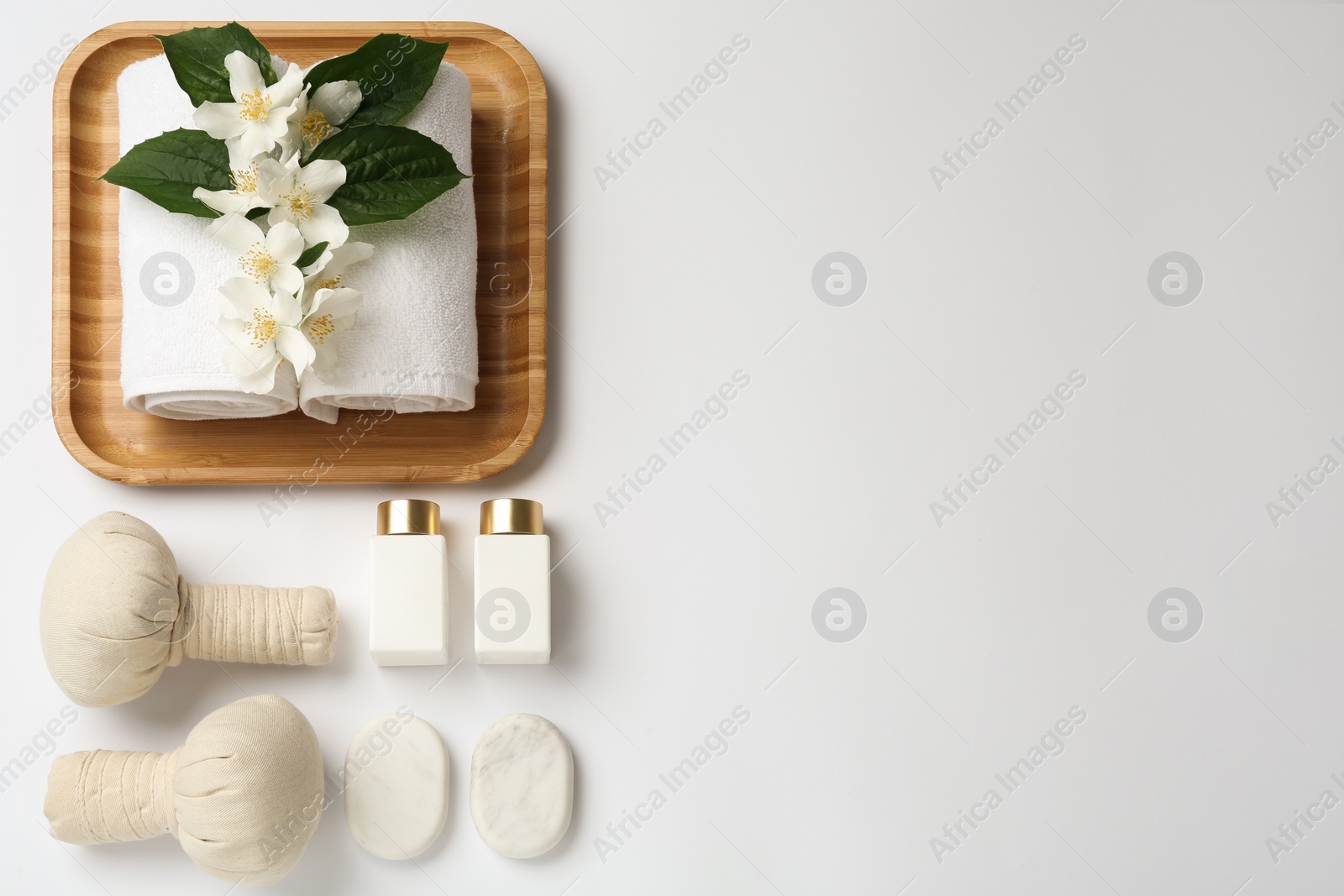 Photo of Flat lay composition with spa stones and beautiful jasmine flowers on white background, space for text