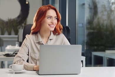 Photo of Happy woman working with laptop at white desk in office