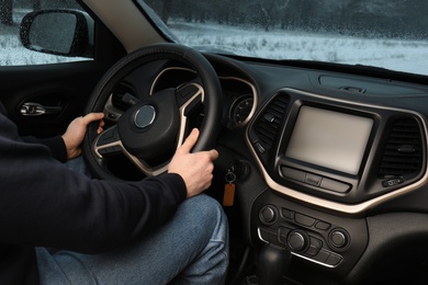 Young man driving car along winter forest, closeup