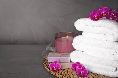 Composition with towels and orchid flowers on grey stone surface, space for text