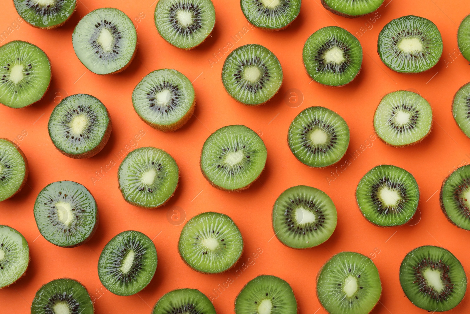 Photo of Many cut fresh ripe kiwis on orange background, flat lay