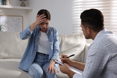 Photo of Unhappy young woman having session with her therapist indoors