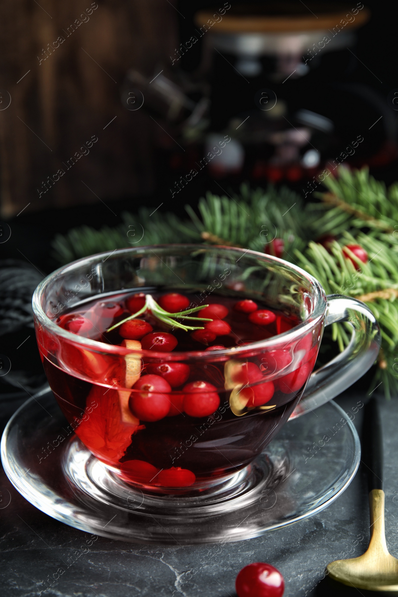 Photo of Tasty hot cranberry tea with rosemary and lemon on black table