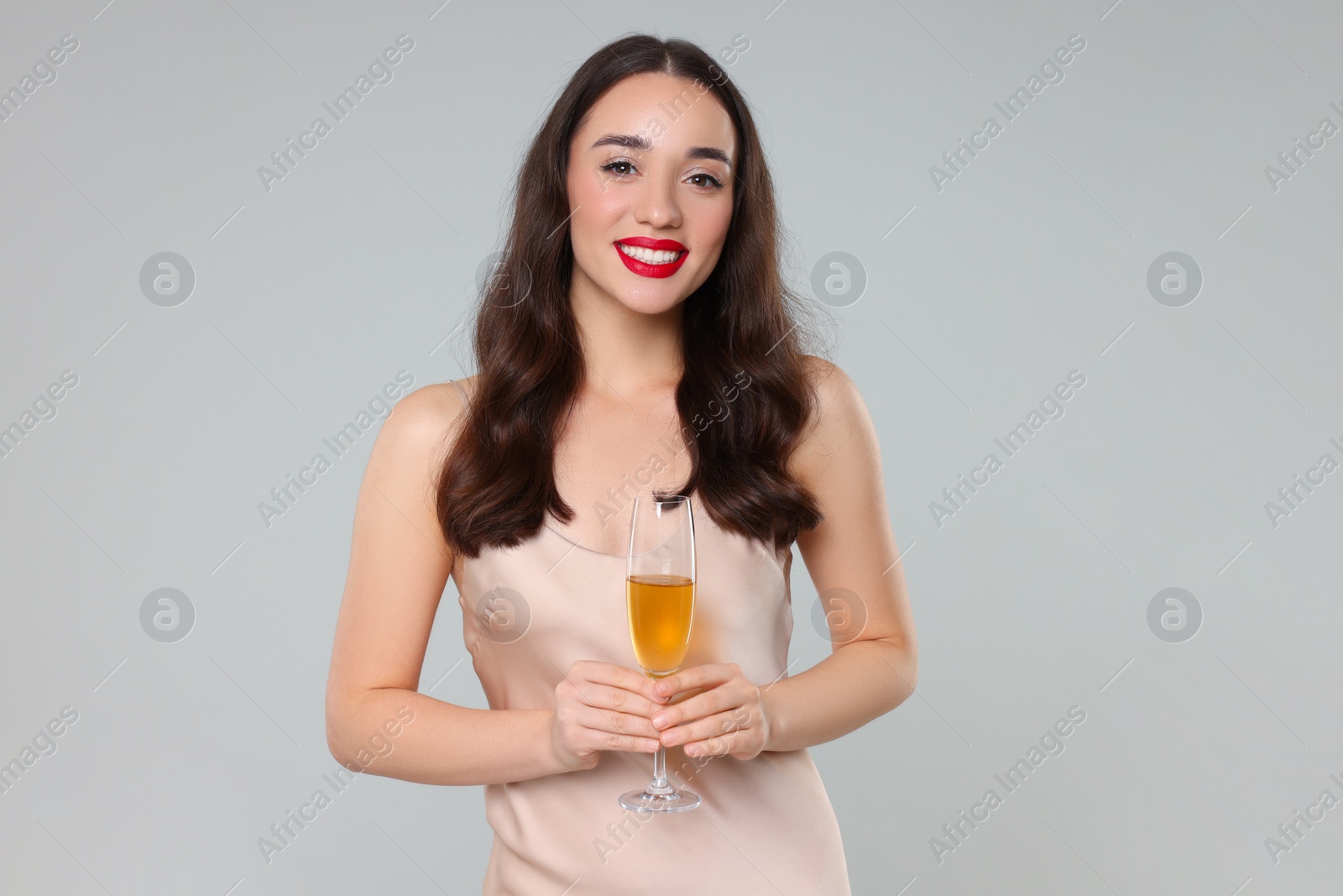 Photo of Christmas celebration. Beautiful young woman with glass of champagne on grey background