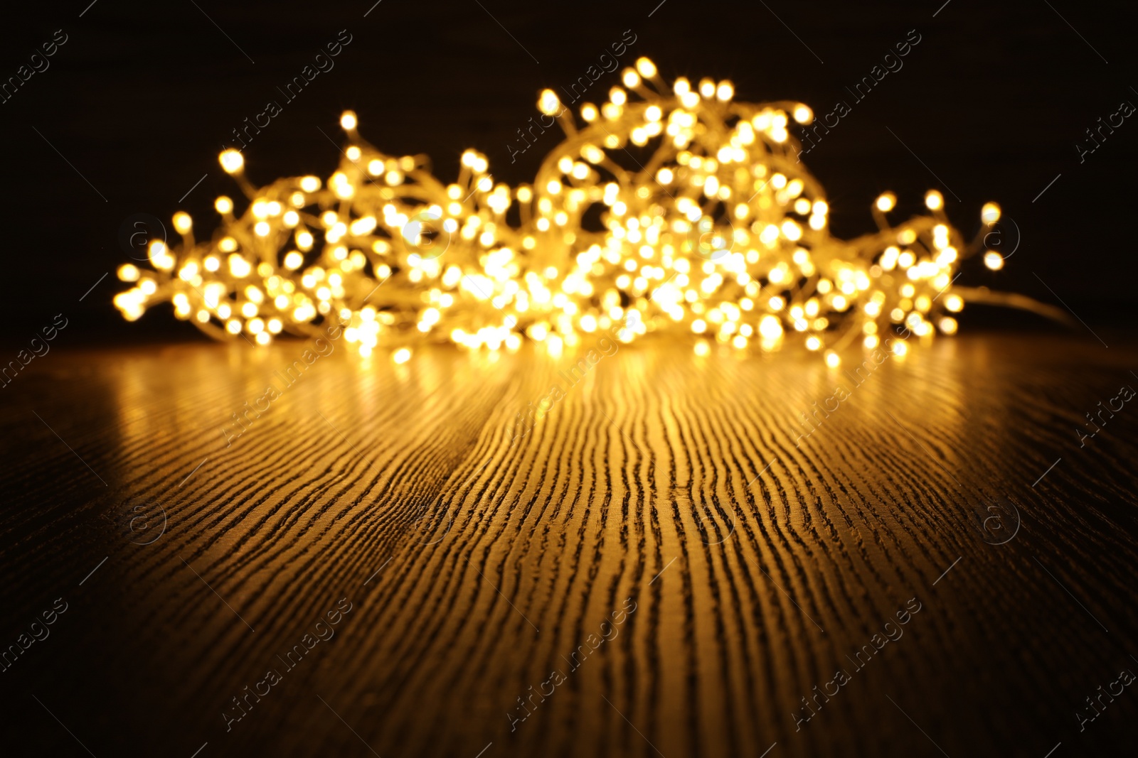 Photo of Beautiful glowing Christmas lights on wooden table. Space for text