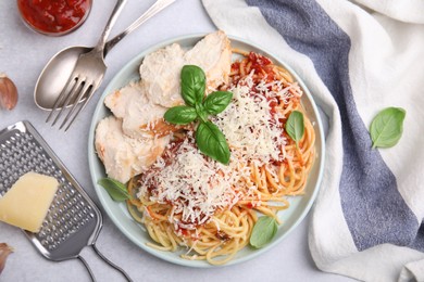 Delicious pasta with tomato sauce, chicken and parmesan cheese on white table, flat lay
