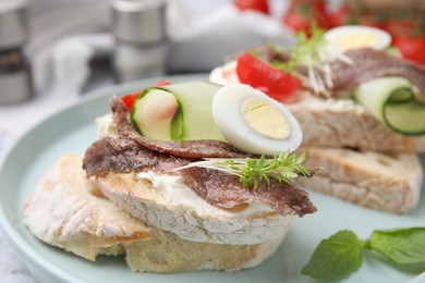 Delicious bruschettas with anchovies, tomato, cucumber, egg and cream cheese on plate, closeup