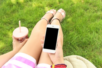 Photo of Woman holding smartphone with blank screen outdoors. Mockup for design