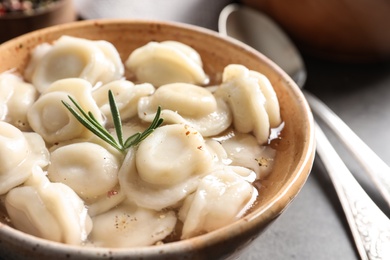 Bowl of tasty dumplings in broth on table, closeup