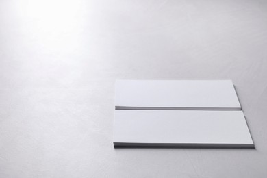 Blank business cards on light grey textured table, closeup. Mockup for design