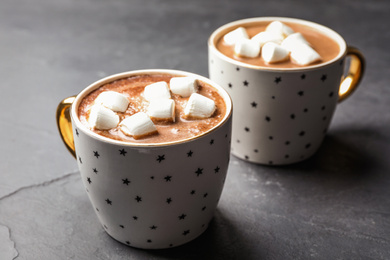 Cups of delicious hot cocoa with marshmallows on grey table