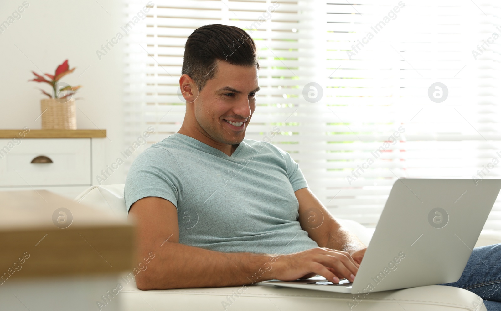 Photo of Man using laptop for search on sofa at home