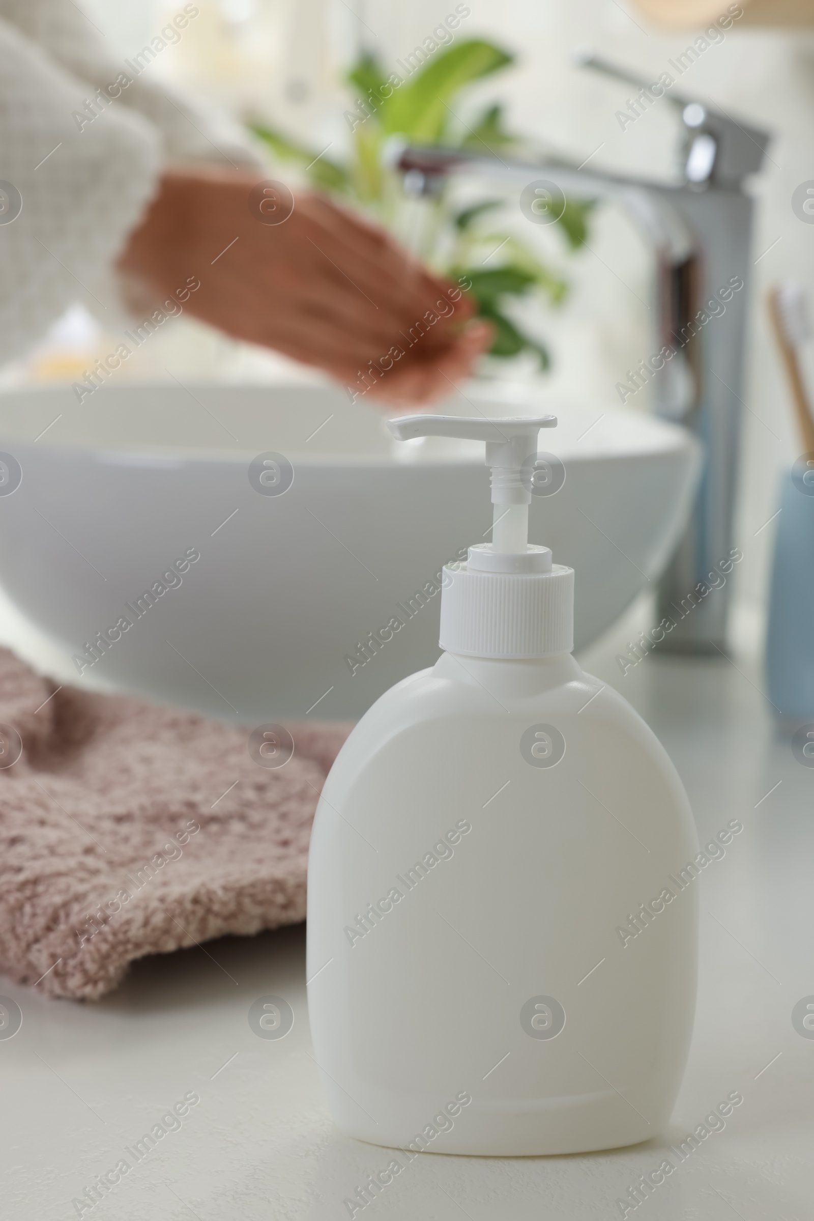 Photo of Woman washing hands with liquid soap in bathroom, focus on dispenser. Space for text