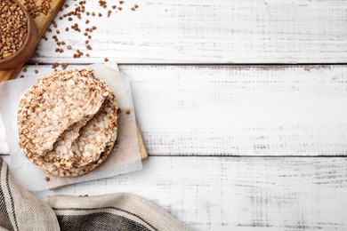 Photo of Crunchy buckwheat cakes on white wooden table, flat lay. Space for text