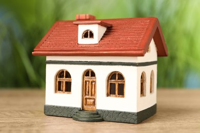 Photo of Mortgage concept. House model on wooden table against blurred green background