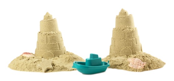Photo of Toy ship between two castles made of sand isolated on white. Beautiful lighthouses