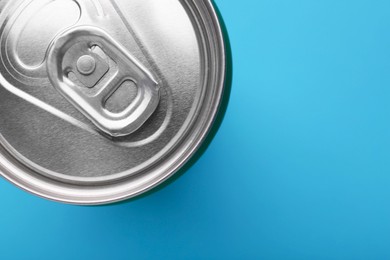 Photo of Energy drink in can on light blue background, top view. Space for text