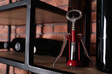 Photo of Bottles of wine and corkscrew on rack, closeup