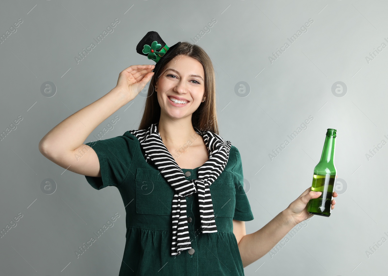 Photo of Happy woman in St Patrick's Day outfit with beer on light grey background