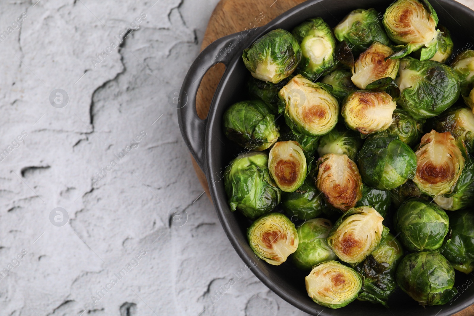 Photo of Delicious roasted Brussels sprouts in baking dish on white textured table, top view. Space for text