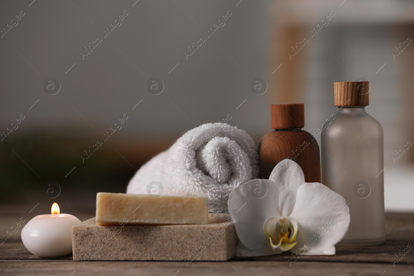 Photo of Composition with spa products, flower and burning candle on wooden table indoors