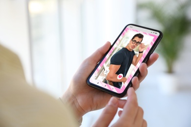 Woman visiting dating site via smartphone indoors, closeup