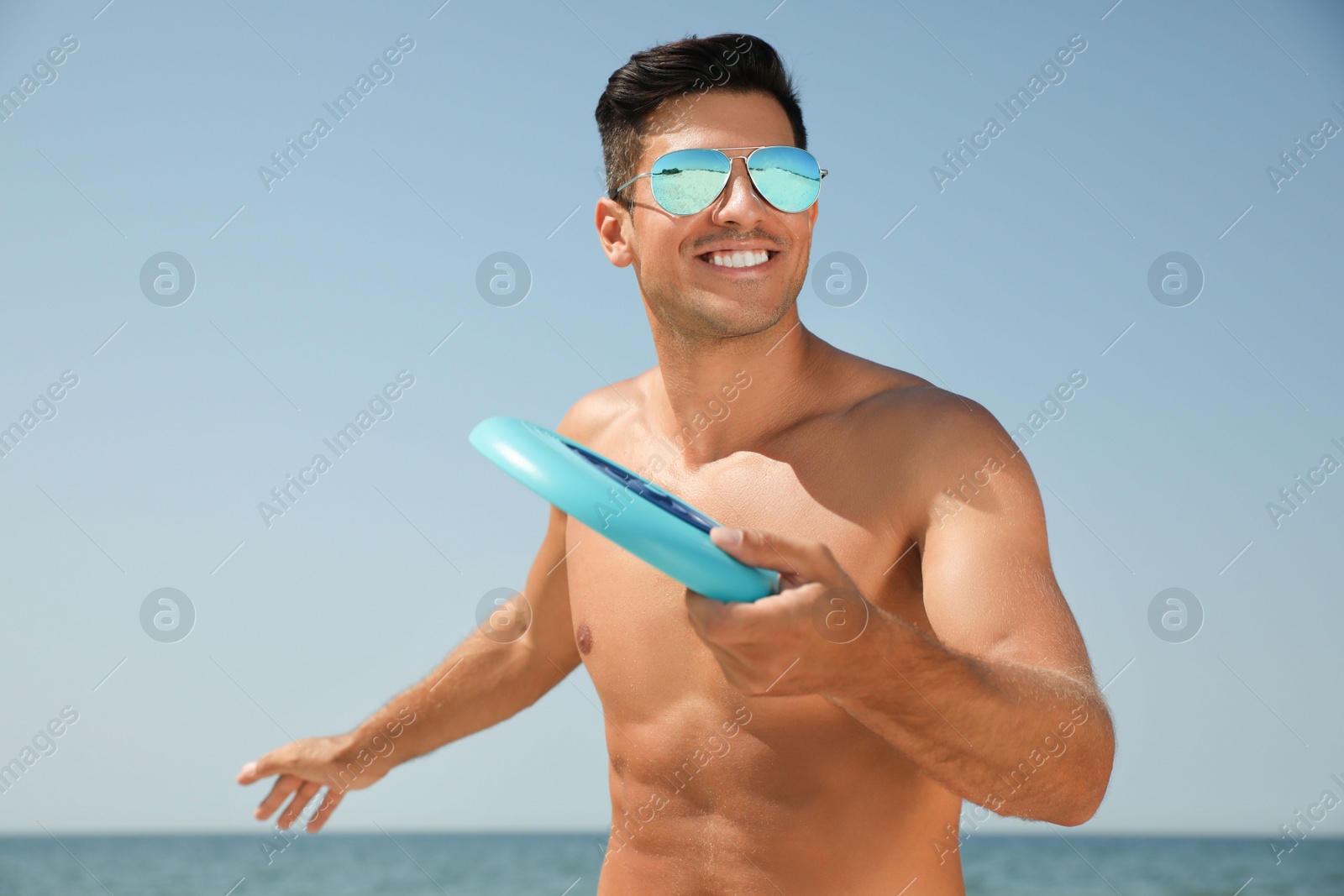 Photo of Happy man throwing flying disk at beach on sunny day