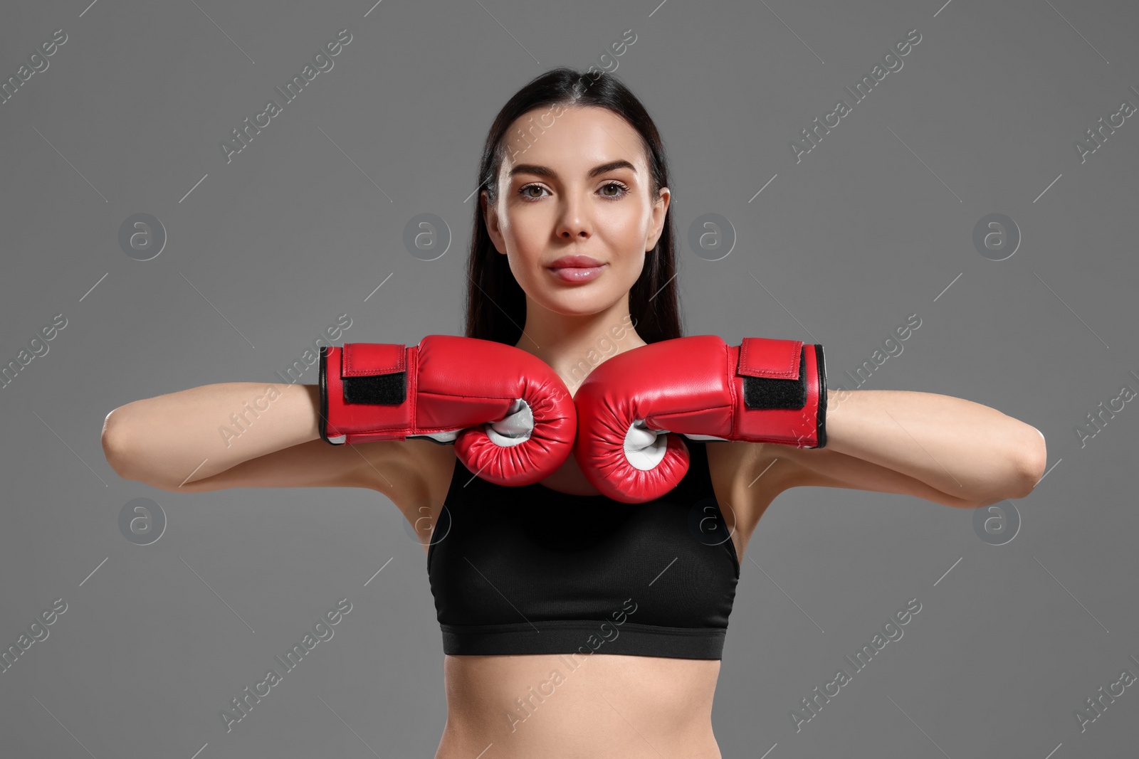 Photo of Portrait of beautiful woman in boxing gloves on grey background