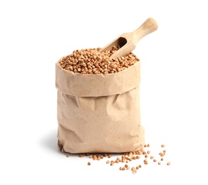 Paper bag with uncooked buckwheat and scoop on white background