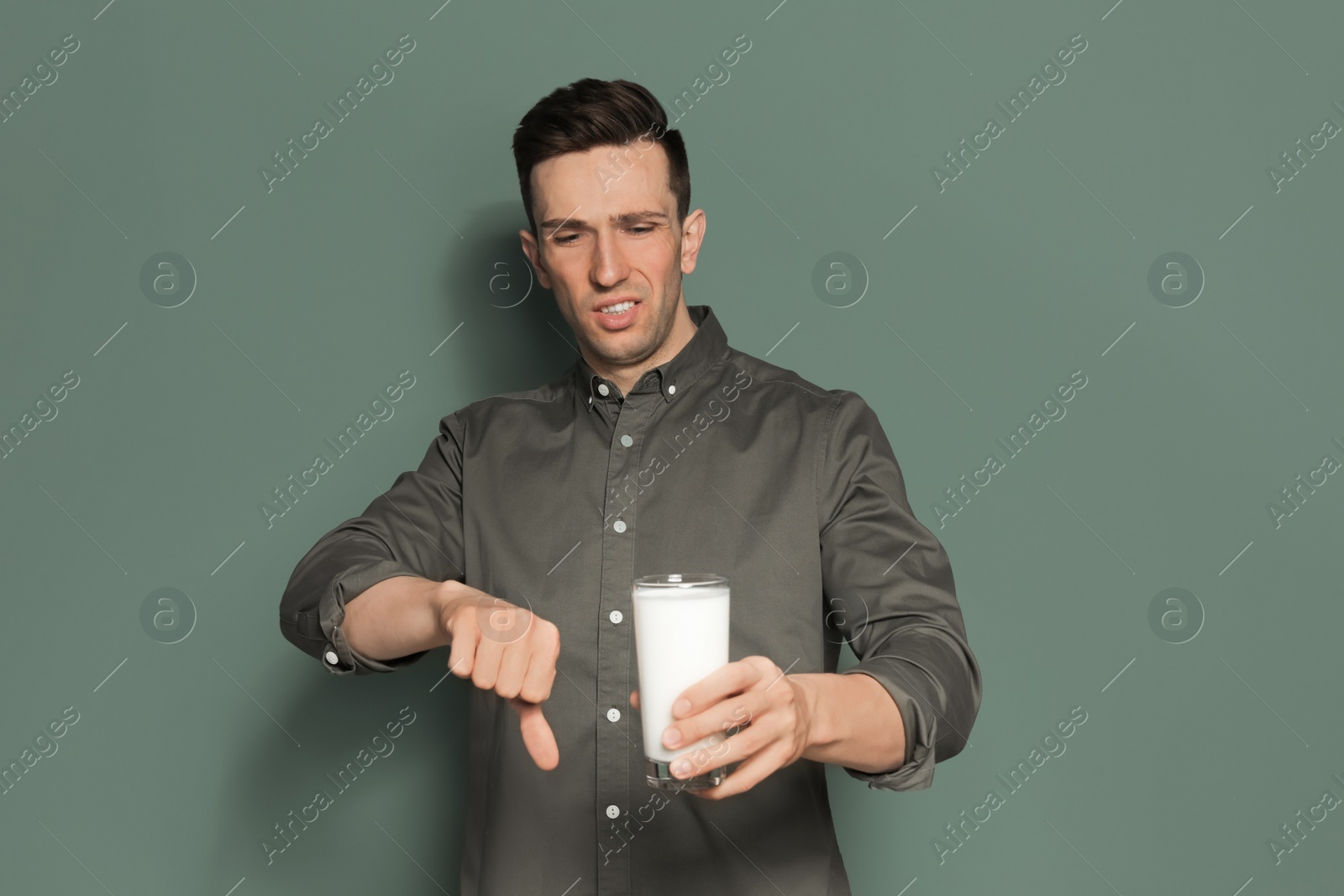 Photo of Young man with dairy allergy holding glass of milk on color background