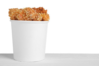 Photo of Bucket with yummy nuggets on table against white background, space for text