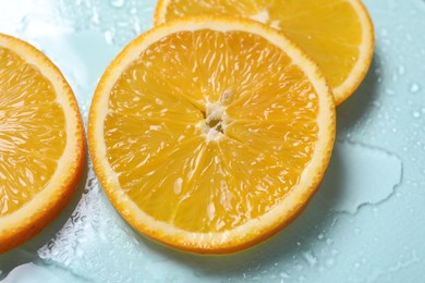 Photo of Slices of juicy orange and water on light blue background, closeup