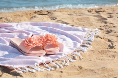 Photo of Blanket with stylish slippers on sandy beach near sea