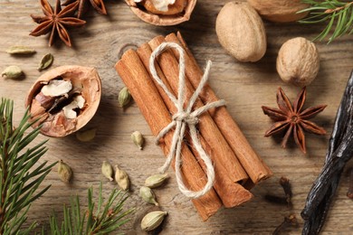 Different spices, nuts and fir branches on wooden table, flat lay