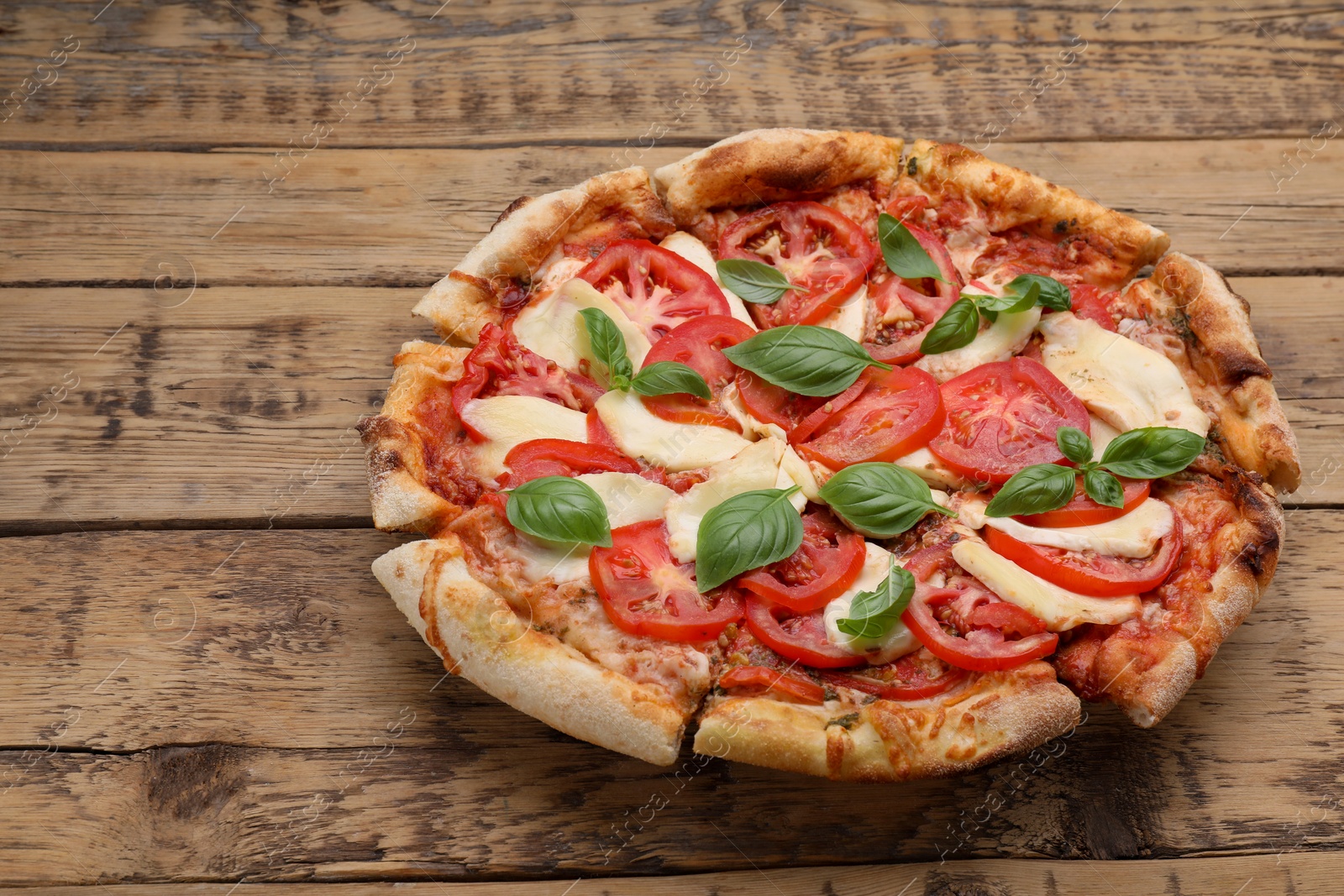 Photo of Delicious Caprese pizza on wooden table, space for text