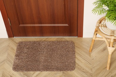 Photo of New clean mat near entrance door and stool with plant