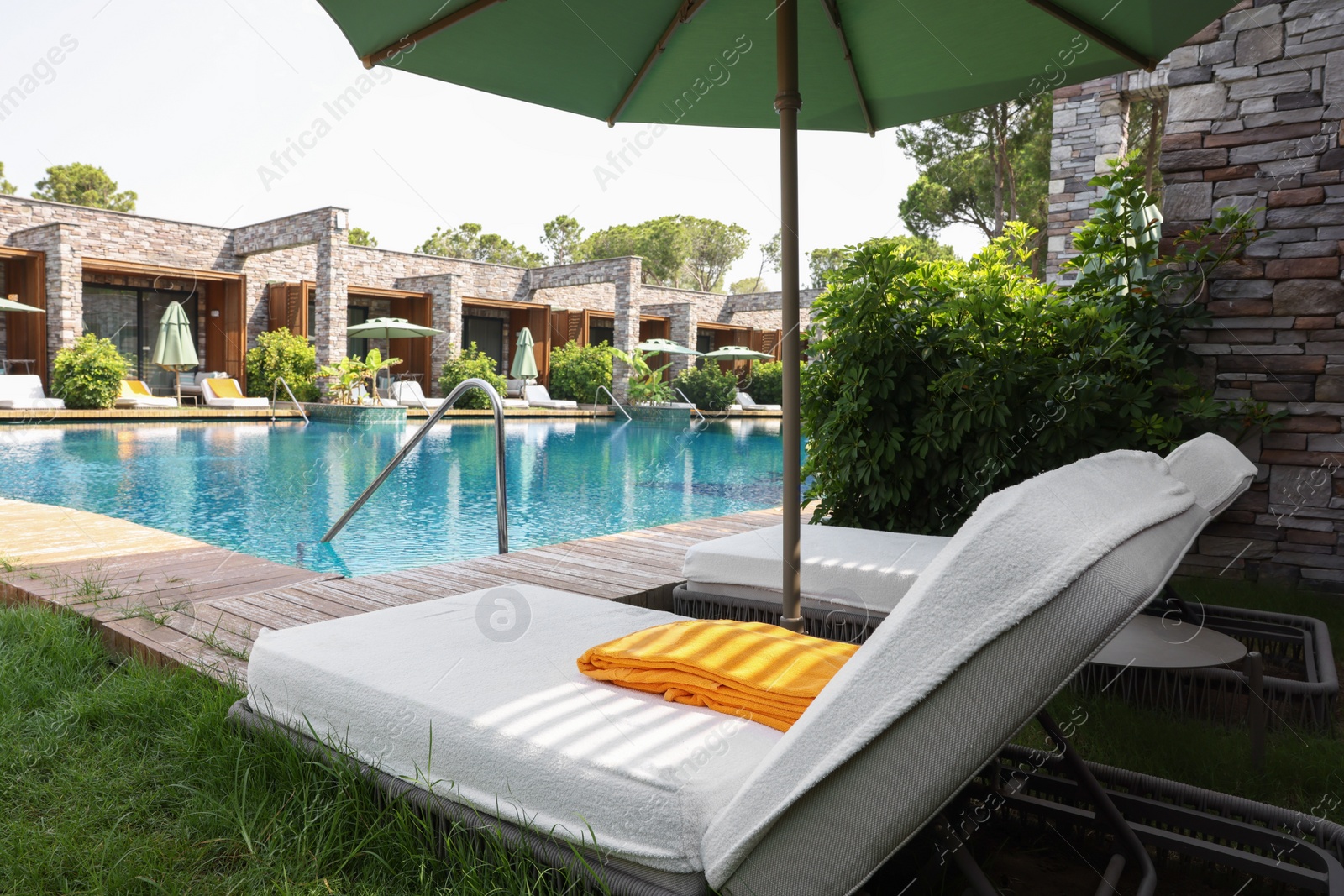 Photo of Sunbeds near outdoor swimming pool at luxury resort