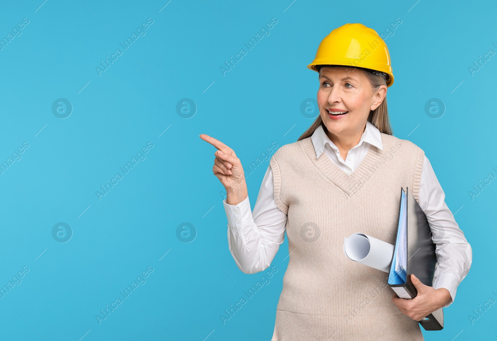 Photo of Architect in hard hat with draft and folder pointing at something on light blue background, space for text