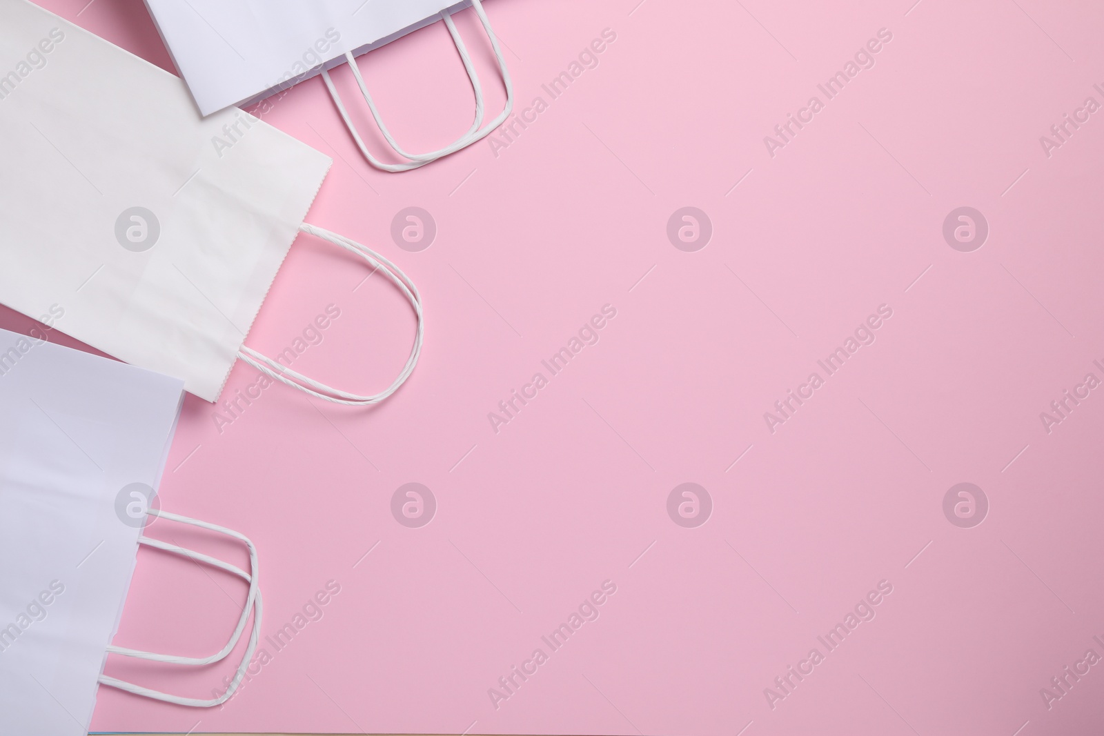 Photo of White paper bags on pink background, top view. Space for text