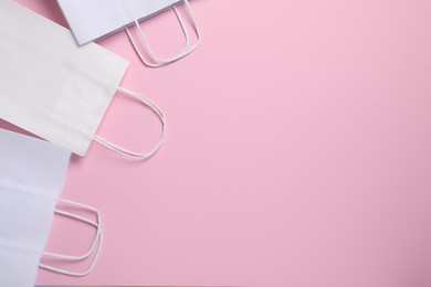 White paper bags on pink background, top view. Space for text