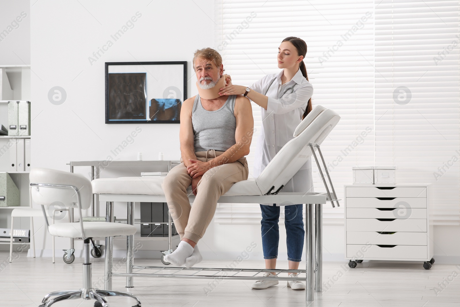 Photo of Orthopedist applying cervical collar onto patient's neck in clinic