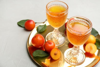 Photo of Delicious plum liquor and ripe fruits on light table. Homemade strong alcoholic beverage