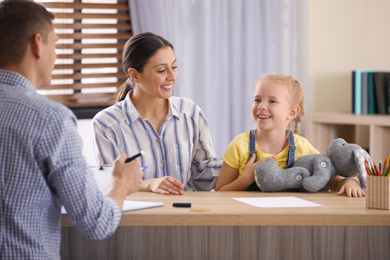 Photo of Child psychotherapist working with little girl and her mother in office