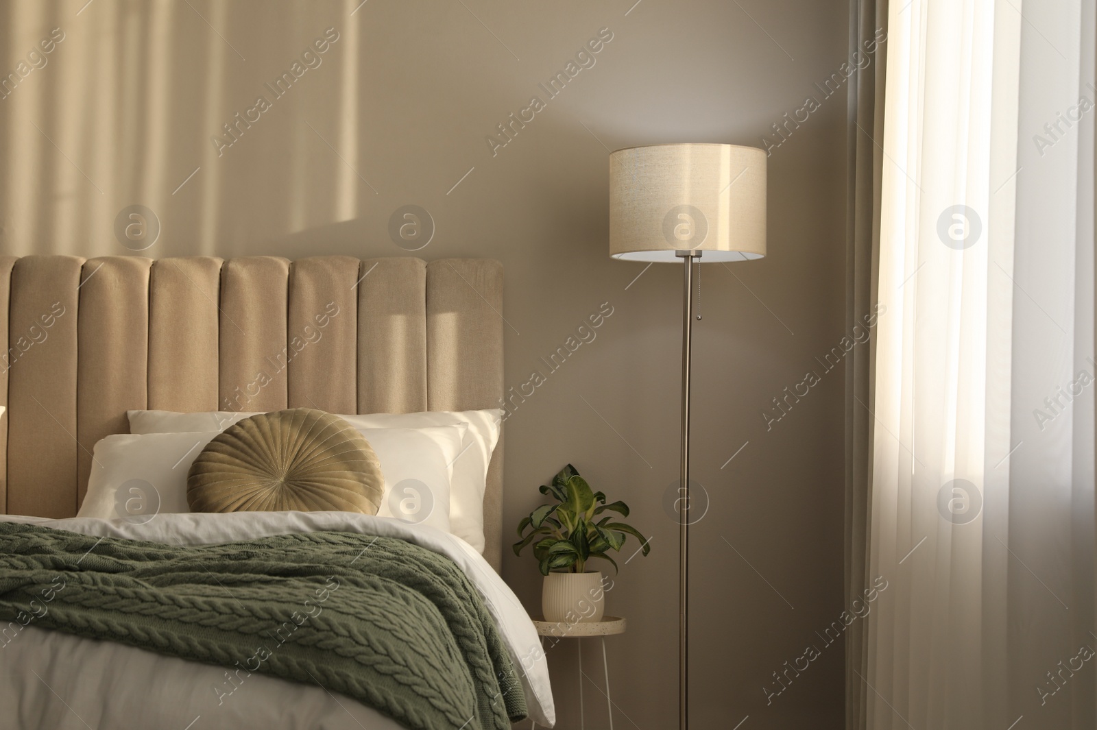 Photo of Stylish floor lamp and plant in bedroom. Interior element