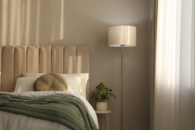 Photo of Stylish floor lamp and plant in bedroom. Interior element