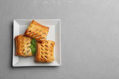 Fresh delicious puff pastry on grey table, top view. Space for text