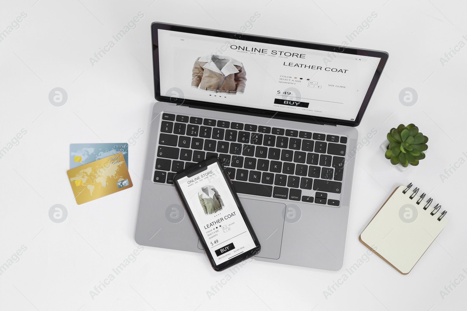 Photo of Online store website on laptop screen. Computer, smartphone, notebook, credit cards and houseplant on white background, flat lay