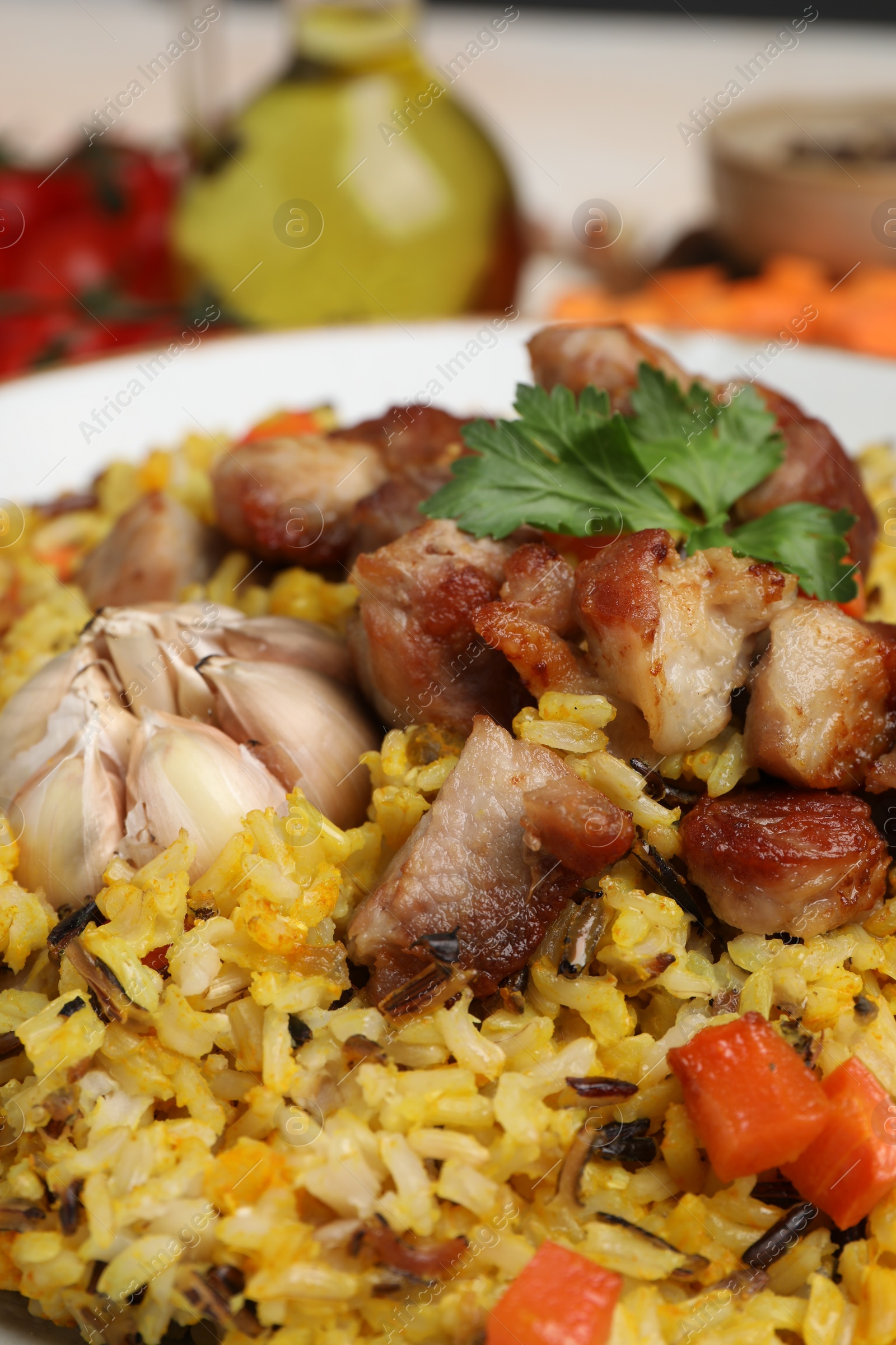 Photo of Delicious pilaf with meat, carrot and garlic on plate, closeup