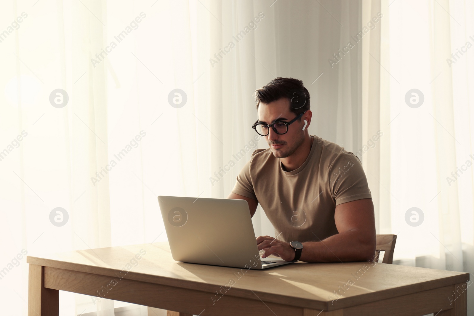 Photo of Portrait of young man with laptop at table indoors